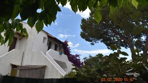 A white building with a sloped roof, surrounded by trees and a fence.