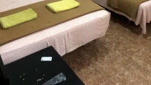 Two single beds with matching headboards and pillows, a bedside table with a remote control, and a wall-mounted thermostat. - Rooms Barco (Madrid)