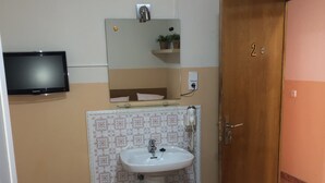 A small, clean room with a bed, a sink, a mirror, and a television. - Rooms Barco (Madrid)