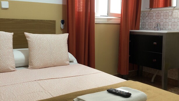 A hotel room with a bed, a desk, a chair, and a window with curtains. - Rooms Barco (Madrid)