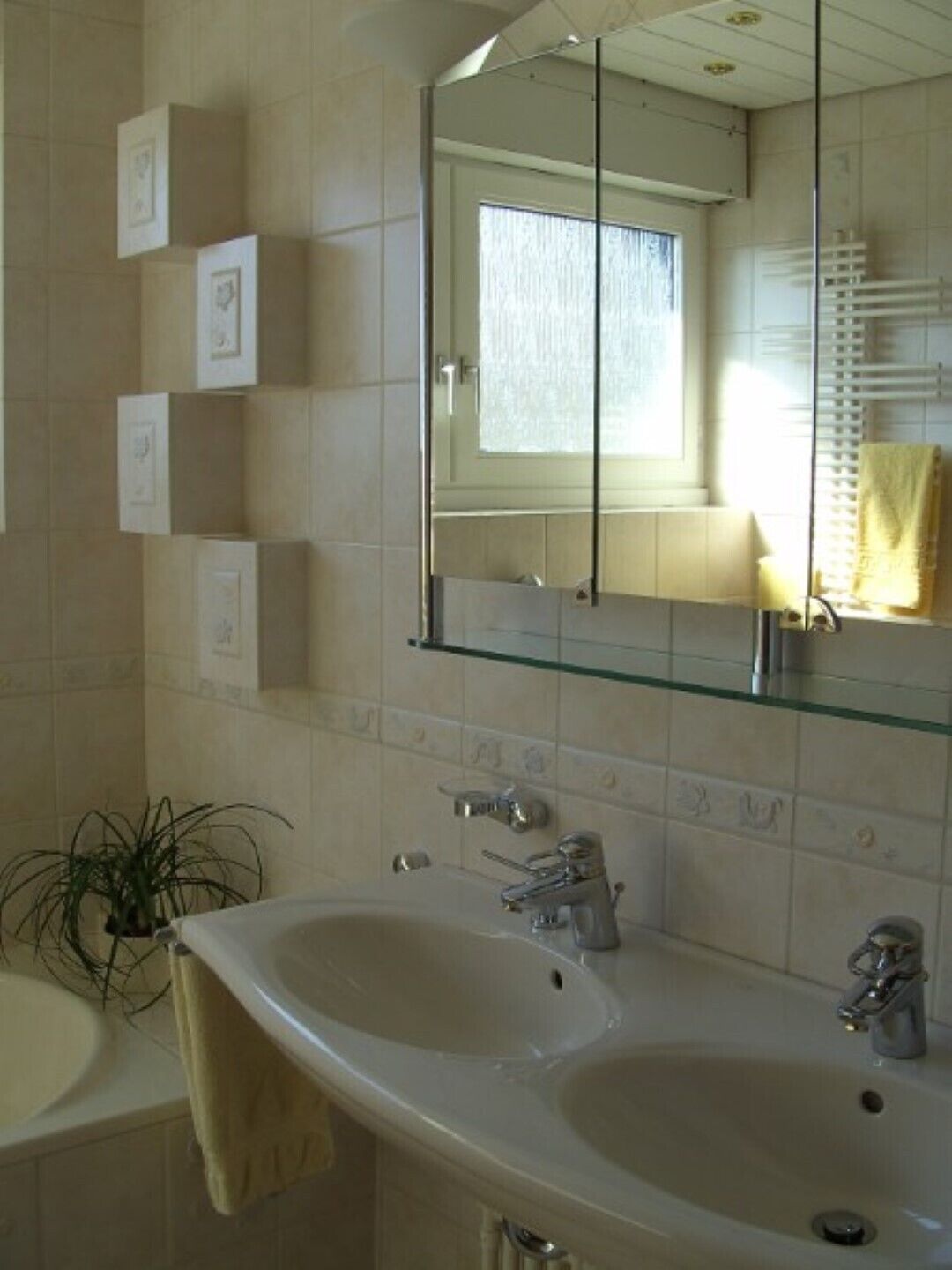 Une salle de bain avec deux lavabos, un miroir et une fenêtre.