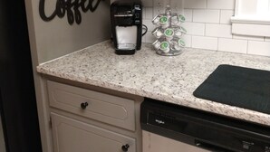 A kitchen with a coffee maker, a coffee mug, and a wall sign that says "Coffee".