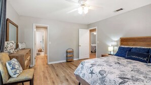 A bedroom with a bed, a chair, a dresser, and a ceiling fan. - Life's a Breeze | 5min to Pcola Beach • Families (Gulf Breeze)