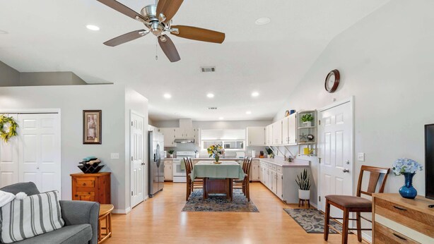 A modern kitchen with white cabinets, a dining area with a table and chairs, and a ceiling fan. - Life's a Breeze | 5min to Pcola Beach • Families (Gulf Breeze)