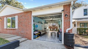 A garage with a workbench, storage shelves, and a large barrel. - Life's a Breeze | 5min to Pcola Beach • Families (Gulf Breeze)