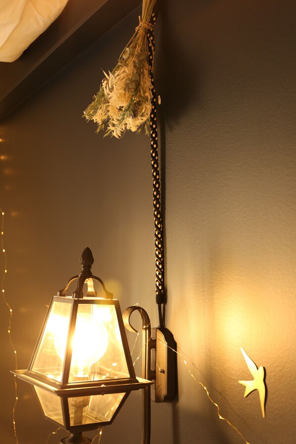 A wall-mounted lantern with a clear glass enclosure, a decorative hanging element, and a wall-mounted light switch. - Charming loft in the heart of Tours, in a quiet and ideal location (Tours)