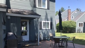 A deck with a grill, chairs, and a table.