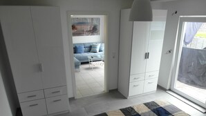 Un dormitorio con cama, armario y vistas a un espacio exterior.