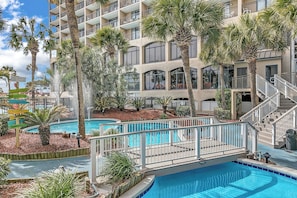 A hotel with multiple balconies, a swimming pool, and palm trees. - Classy & coastal oceanfront condo- Pools, hot tubs, pool bar, lazy river! (North Myrtle Beach)