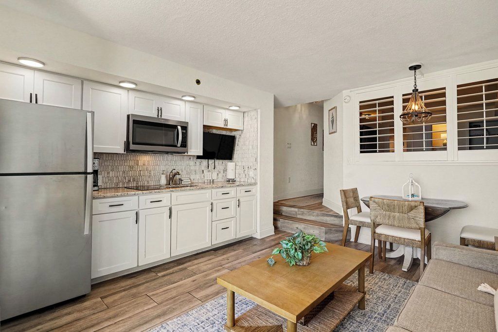Una cocina moderna con armarios blancos, electrodomésticos de acero inoxidable y una mesa de comedor de madera.