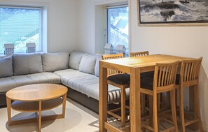 Ett mysigt vardagsrum med en soffa, ett matbord i trä med stolar och ett runt träbord.