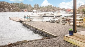 A marina with boats docked, a rocky shoreline, and a wooden dock. - Amazing apartment in Fjell with WiFi (Fjell)