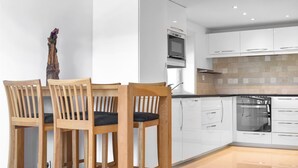 A modern kitchen with white cabinetry, a built-in oven, and a dining area with wooden chairs. - Amazing apartment in Fjell with WiFi (Fjell)