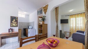 Espaço compacto com área de refeições, cozinha compacta e televisão.