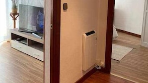 A room with a wooden floor, a white radiator, and a television on a wooden stand. - Arostegi Etxea - unique apartment next to the port (Bermeo)