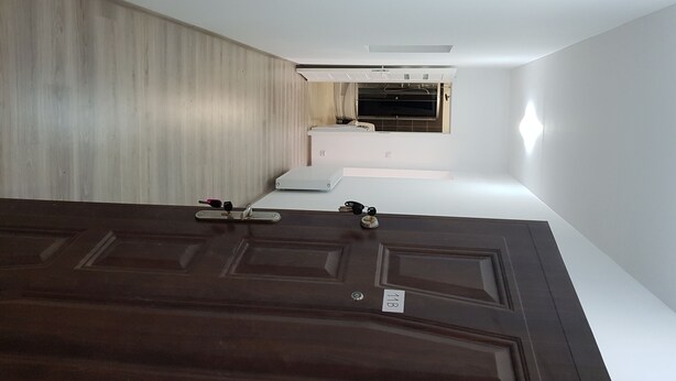 Una habitación con una puerta de madera oscura, una pared blanca y un ventanal pequeño.