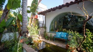 A serene garden with a small pond, a bench, and various plants. - Santa Monica Beach Luxury Suite (Santa Monica)
