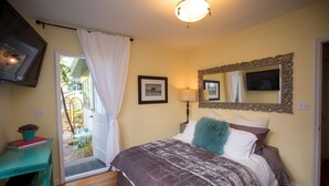 A bedroom with a bed, a mirror, a lamp, and a door leading to a balcony. - Santa Monica Beach Luxury Suite (Santa Monica)