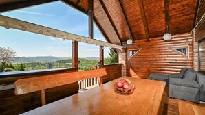 A wooden cabin with a dining table, a bench, and a gray sofa.