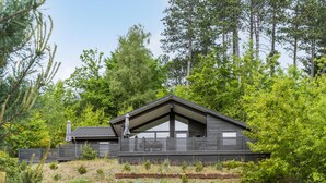 A modern cabin with a sloped roof, large windows, and a wooden exterior. It is surrounded by dense forest and has a natural, secluded setting. - Beautiful home in Ebeltoft with kitchen (Ebeltoft)