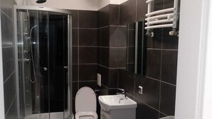 Un bany compacte amb dutxa d'envidriament, vàter, rentapousa i rentadora.
