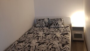 Un dormitori amb un estovat estampat, un quadre penjat a la paret i llum d'ambient suspès.