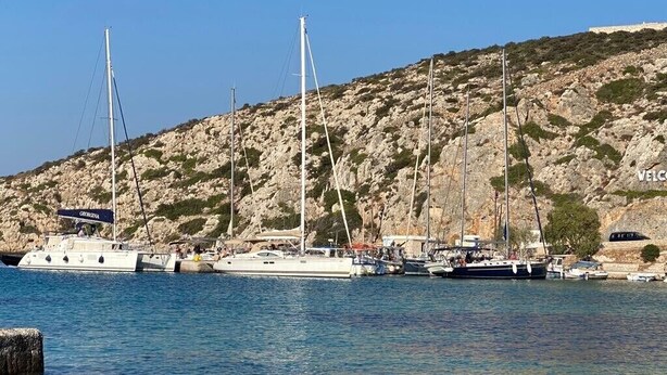 A marina with several sailboats docked, rocky hills in the background, and a clear blue sky. - GREECE, EXCLUSIVE HOLIDAY on Sailing yacht from ATHENS, wIth SKIPPER and CHEF (Lefkada)