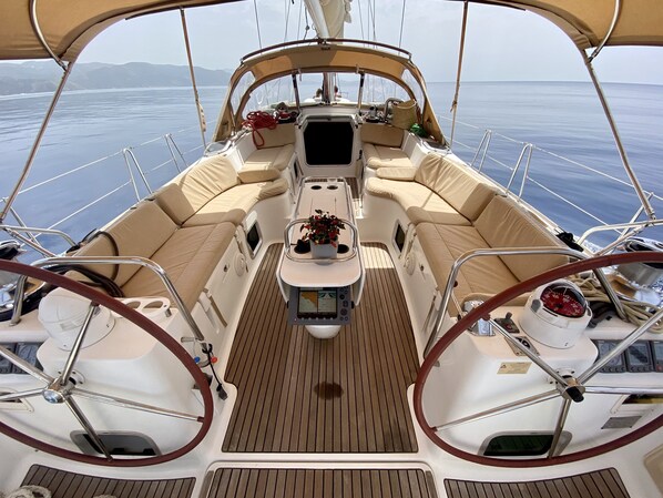 A boat deck with a central seating area, a steering wheel, and a control panel.