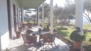 A covered patio with wicker furniture and potted plants. - Leconfield House, the heart of the Hunter Valley, built 1872, 150yrs in 2022 (Leconfield)