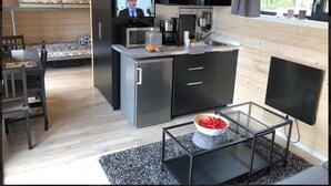 A compact, modern kitchen with a built-in TV, a dining area with a table and chairs, and a cozy seating area with a sofa.
