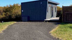 A small, single-story building with a dark blue exterior, a covered porch, and a gravel driveway.