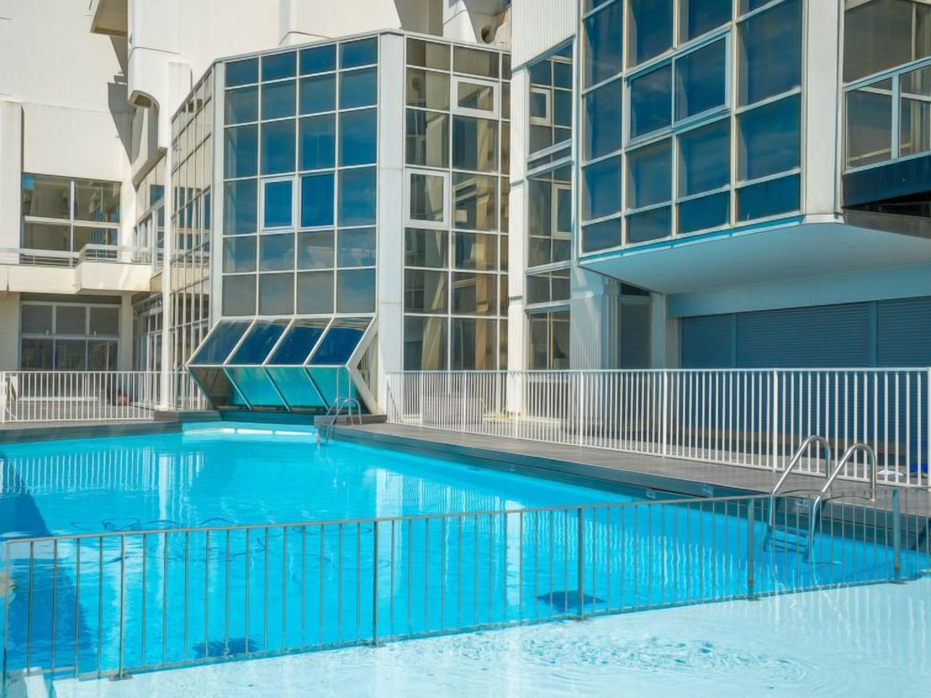 A modern hotel with a large indoor swimming pool, surrounded by glass windows and balconies.