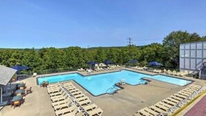 A swimming pool with lounge chairs and umbrellas, surrounded by greenery. - Beautiful Bi-level. Game room with pool table, 5 UHDTVs, WiFi. Central heat/air. (Bushkill)
