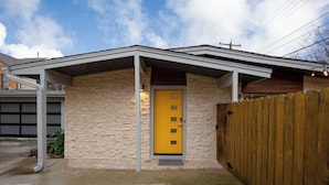 Une maison de plain-pied avec une façade en pierre, une porte jaune et une clôture en bois.