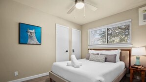 A bedroom with a bed, a window with blinds, a ceiling fan, and a framed picture on the wall. - 7-Minute Walk to Deep Eddy Pool! Parking + Grill (Austin)