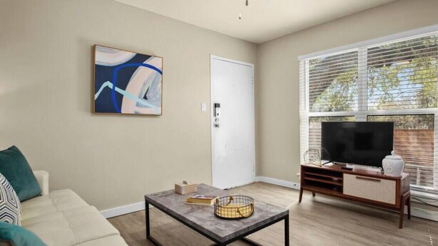 A living room with a sofa, coffee table, TV stand, and artwork on the wall. - 7-Minute Walk to Deep Eddy Pool! Parking + Grill (Austin)