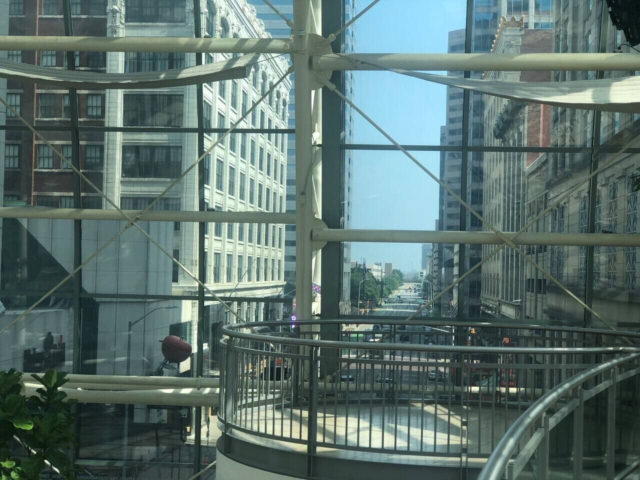 Un edificio alto con fachada de vidrio y un balcón circular con barandilla de metal.