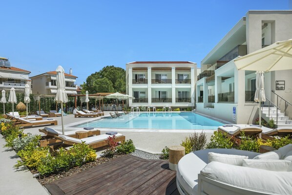 A pool area with lounge chairs, umbrellas, and a wooden deck.