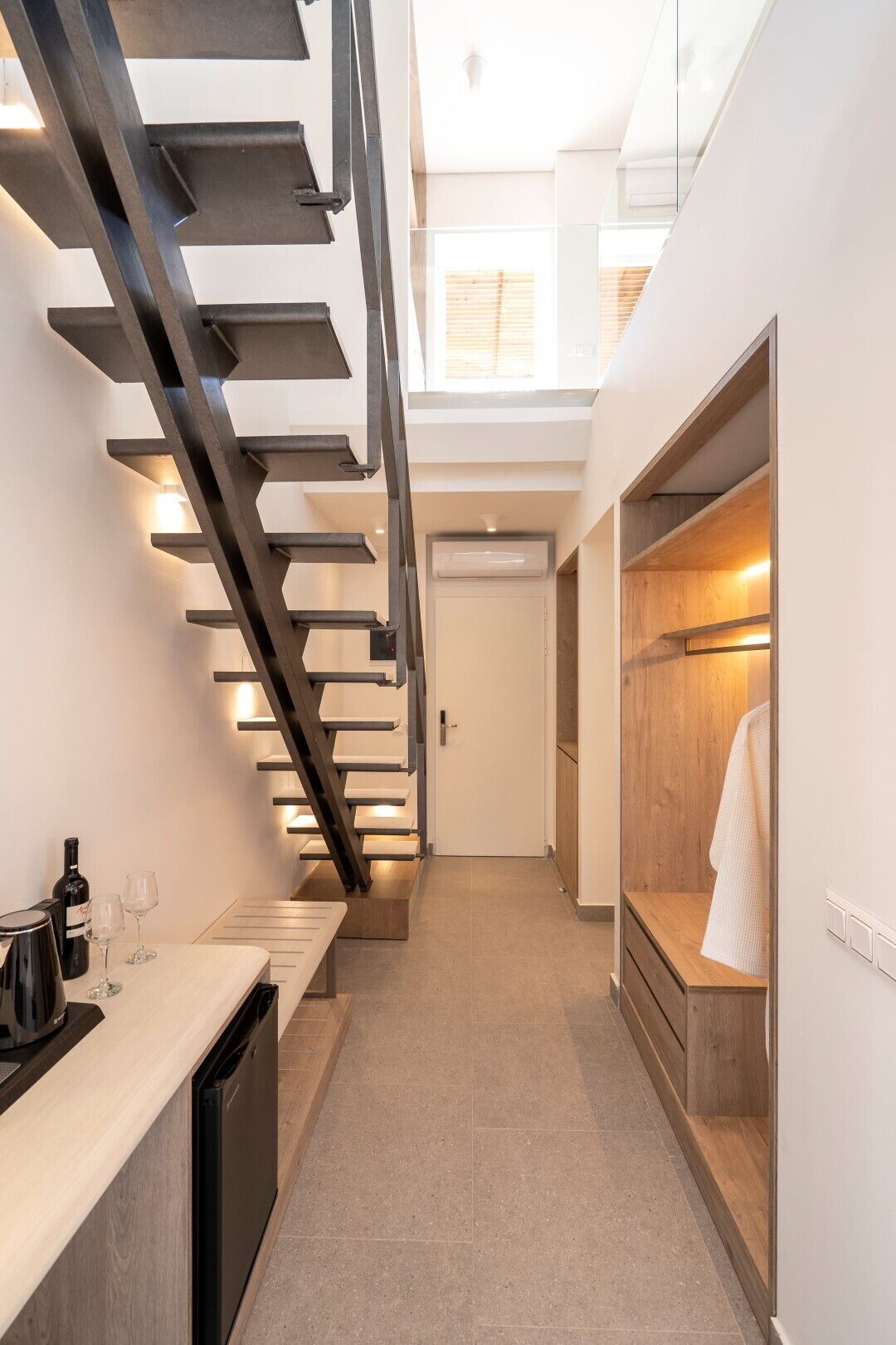 A modern kitchen with a built-in dishwasher, a wooden countertop, and a staircase with integrated lighting.