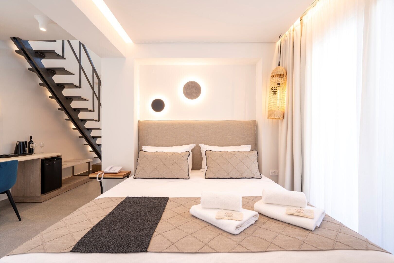 Habitación de hotel moderna con cama, mesita de noche, lámpara y una escalera.
