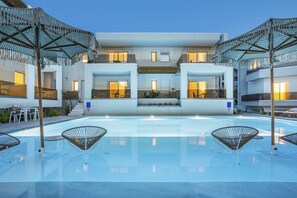 A modern hotel with a central pool, outdoor seating, and a two-story structure. - Mirablue Luxury Residences (Kassandra)