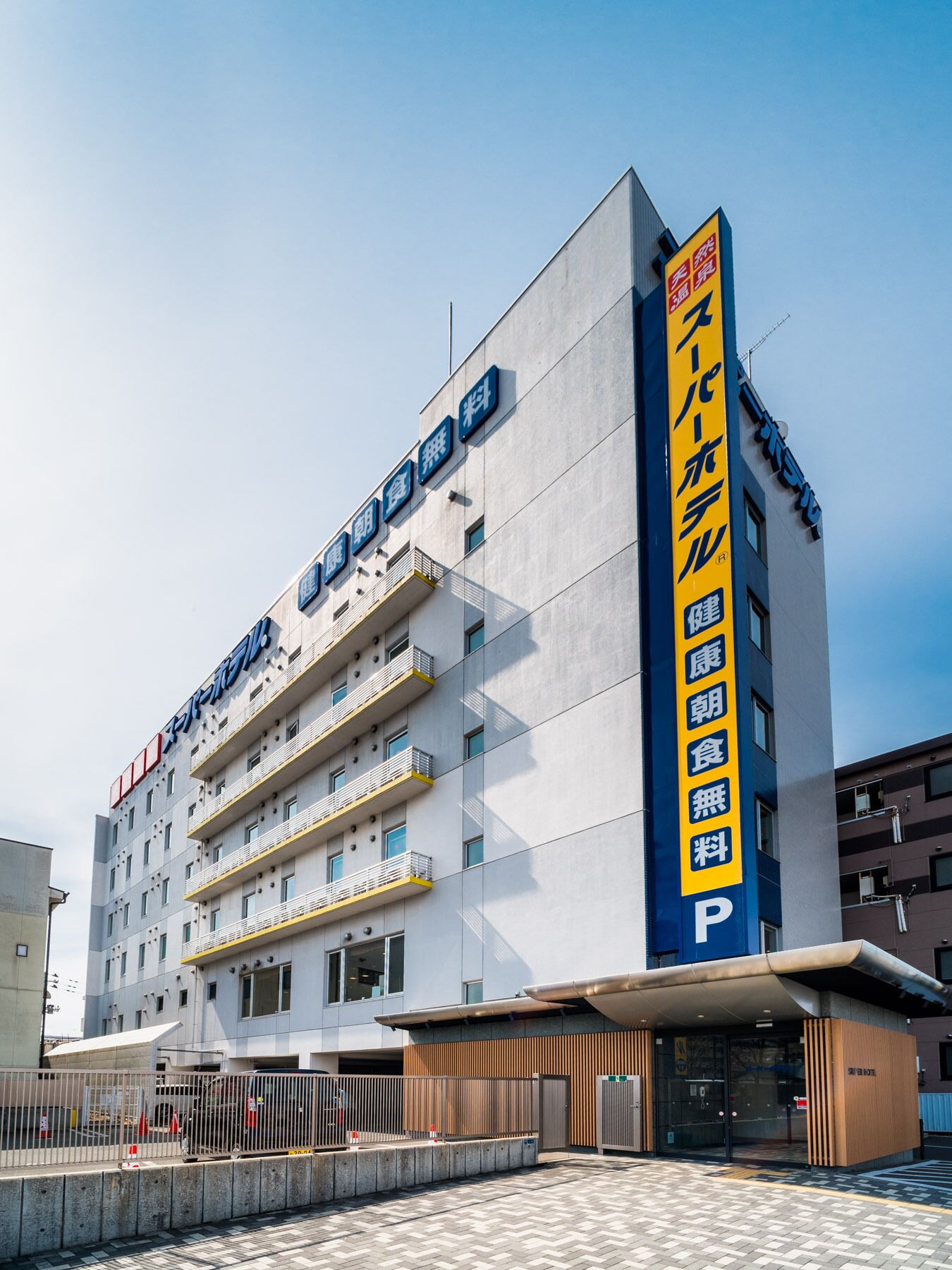 A multi-story hotel with a prominent yellow vertical sign indicating amenities.