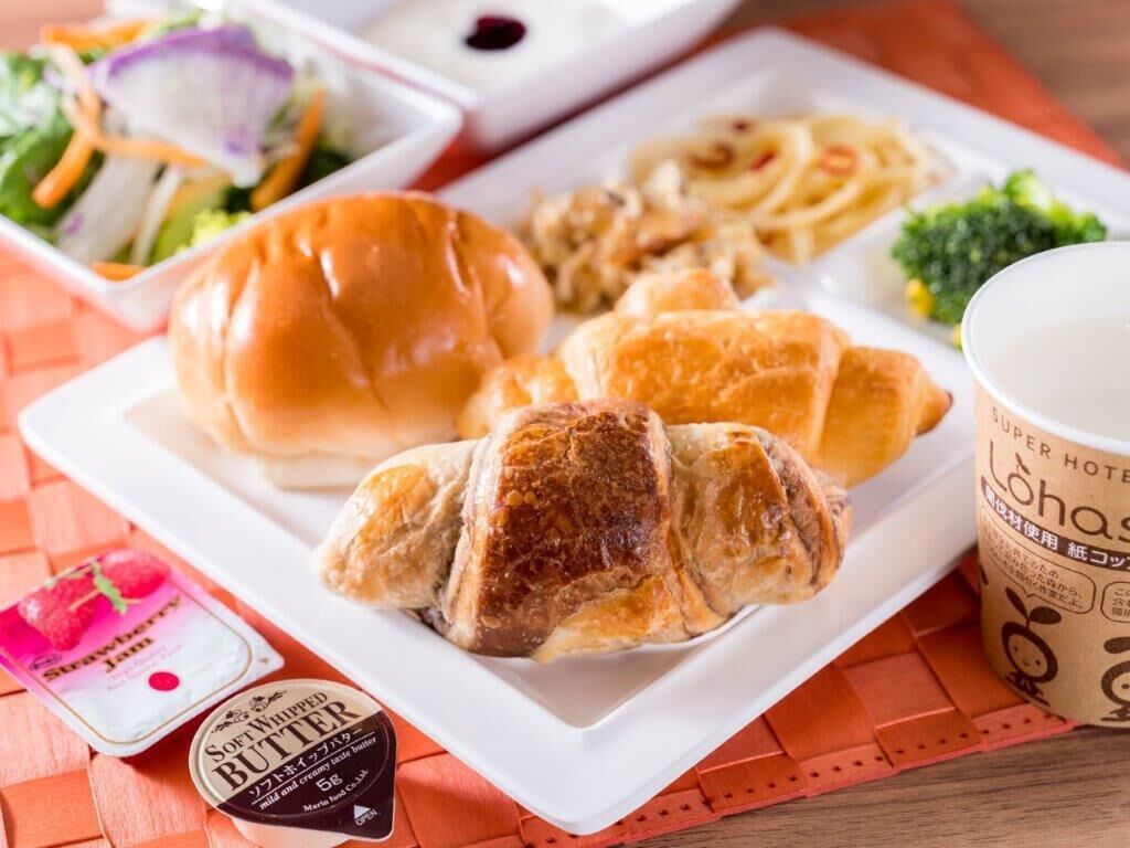 A meal with a sandwich, croissant, pasta, and a cup of coffee on a white plate.