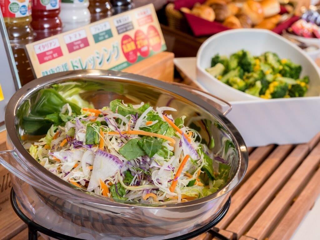 A salad bowl with mixed greens and shredded carrots on a wooden table.