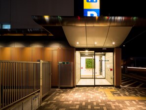 Une entrée moderne avec une porte en verre, un mur en bois à lattes et un auvent en métal.