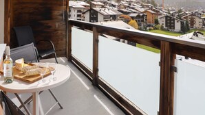 Een balkon met een eettafel, met uitzicht op een woongebied met huizen en bergen op de achtergrond.