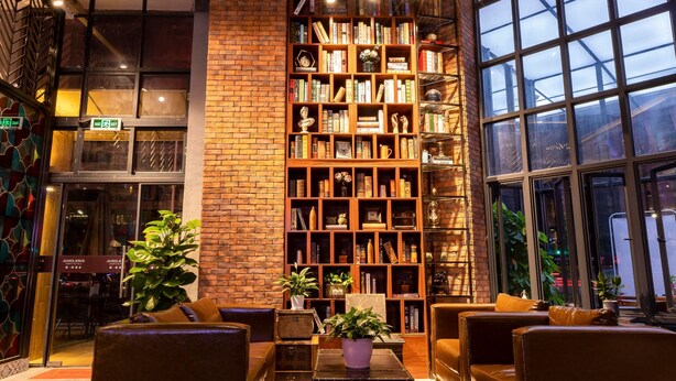 Een gezellige leeshoek met leren banken, een grote boekenkast en een groot raam.