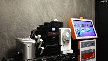Une machine à café, un distributeur d’eau et un kiosque en libre-service dans le hall d’un hôtel.