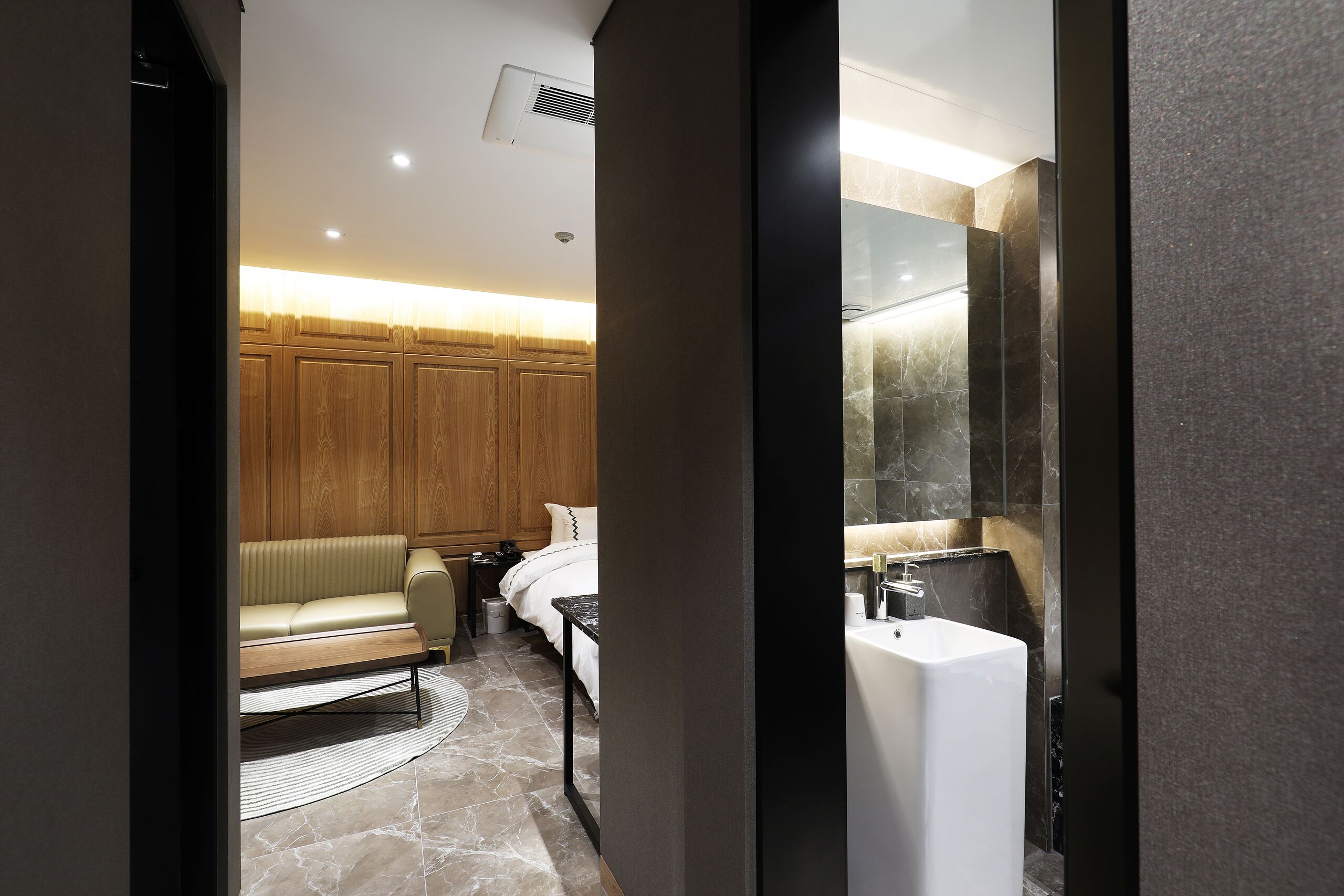 Habitació d'hotel moderna amb llit, taulella de nit i un mirall gran.