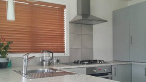 A kitchen with a stainless steel sink, a gas stove, and grey cabinets.